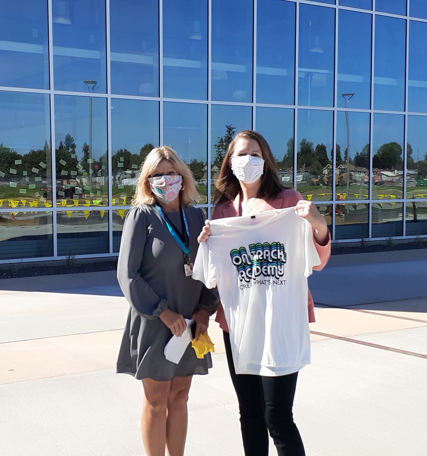 Principal Lisa Mattson and Amber Waldref, ZONE Director, show off the On Track Academy t-shirt in front of the beautiful Engineering lab after the ribbon-cutting.